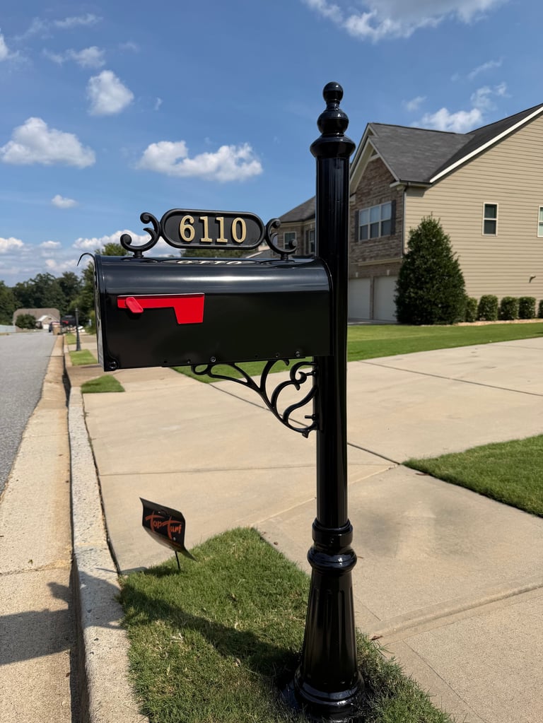 Black decorative mailbox with gold address number 6110 on a post in a residential driveway