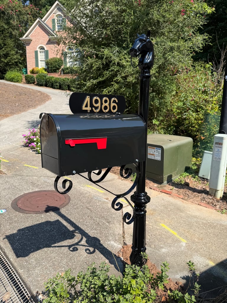 Black decorative mailbox with address number 4986 and ornate post in residential driveway