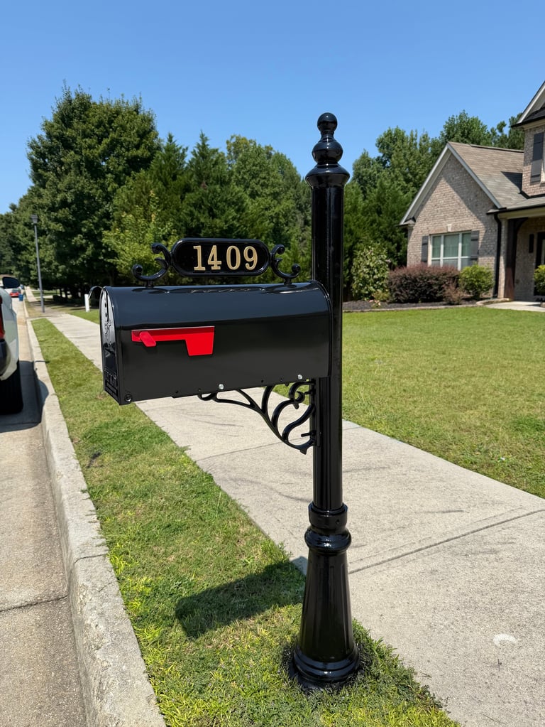 Black mailbox with gold address numbers 14409 mounted on ornamental post in residential driveway