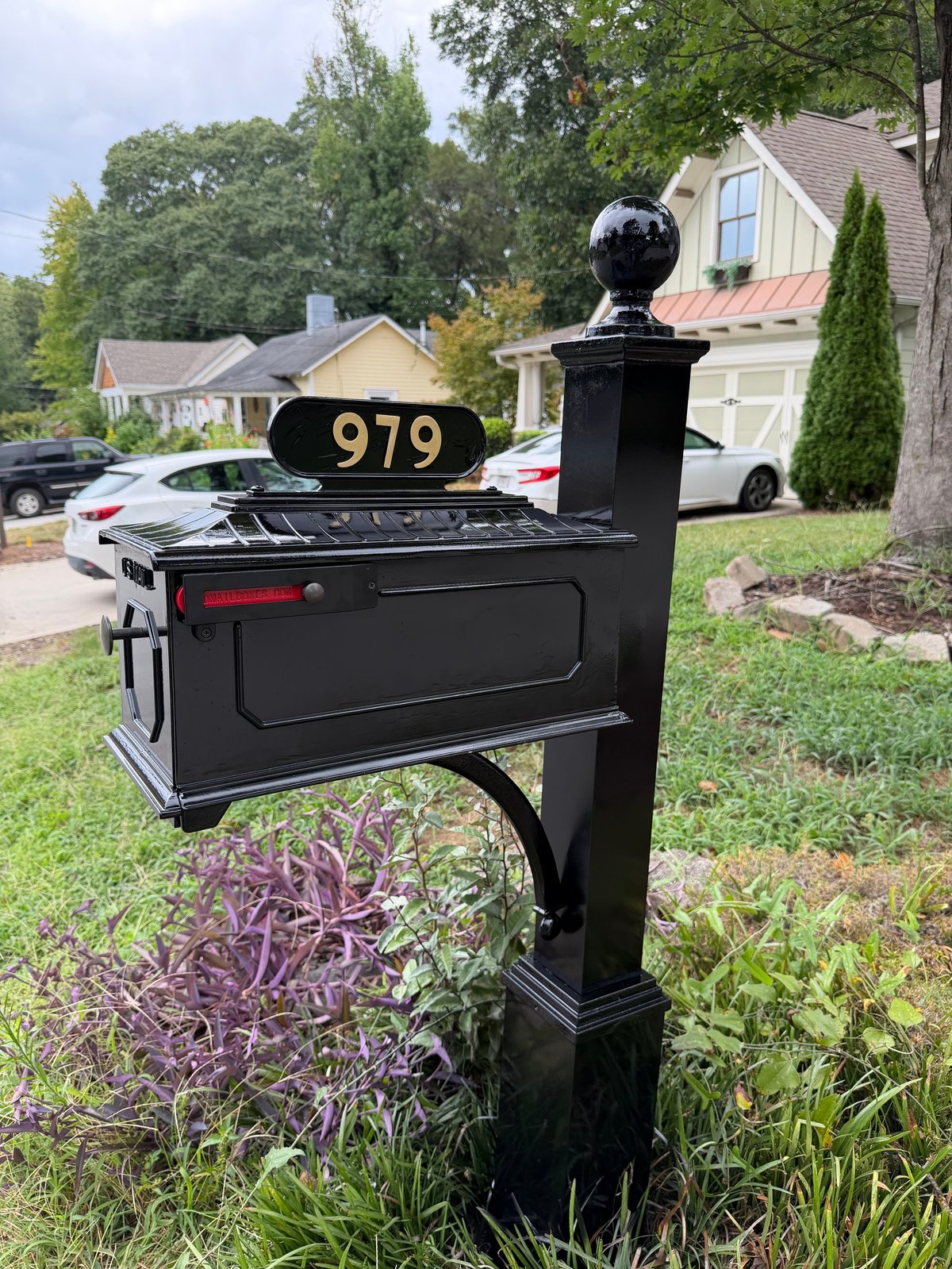 Black mailbox with gold number 979 and ornamental top post on residential driveway